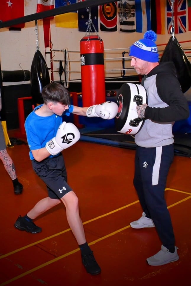 a man and a boy are boxing in a gym