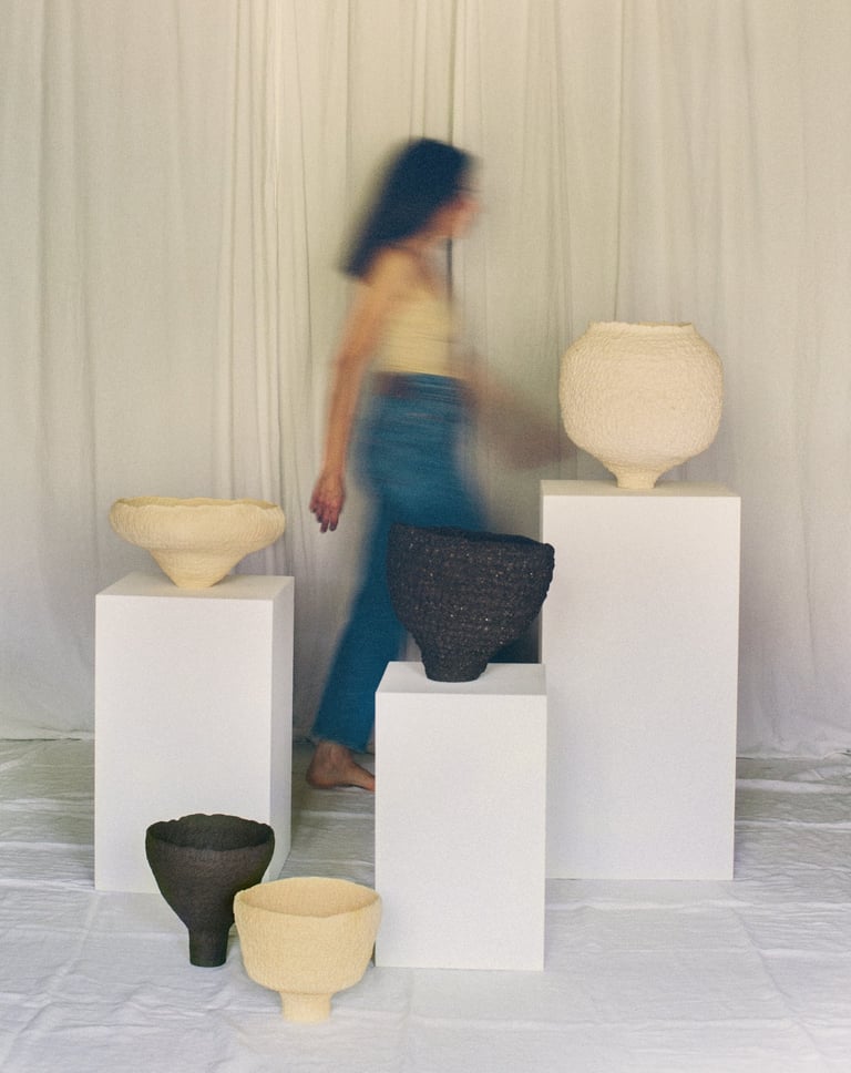 Sabine Segura marchant derrière les sculptures en grès de la série de céramiques Kairos