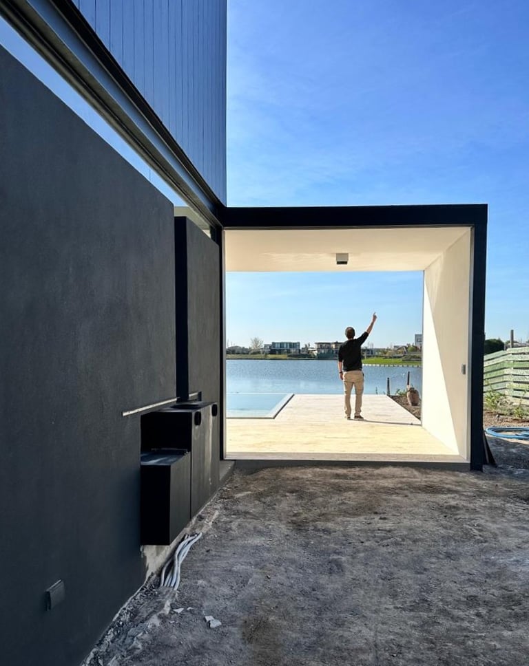  Un hombre parado frente a un edificio con vista a un cuerpo de agua.