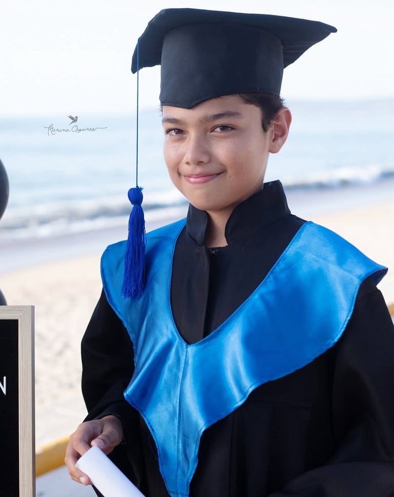 un niño adolescente en una toga en la playa