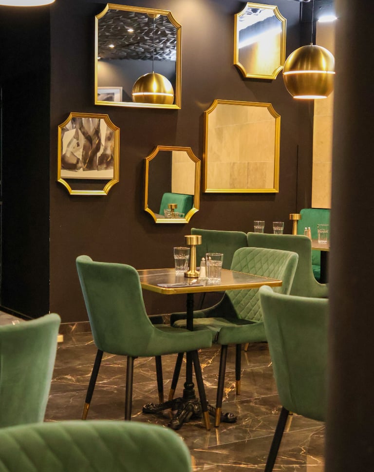 Salle élégante du restaurant La Parisienne à Nîmes avec fauteuils verts et décoration raffinée