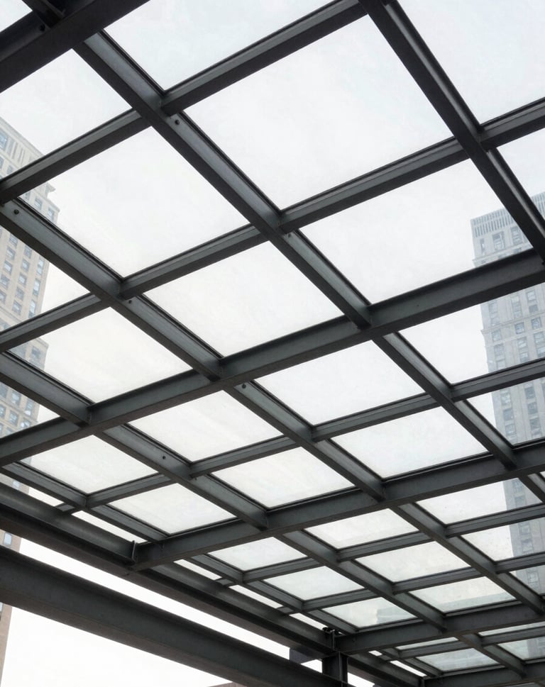 A low-angle shot of a glass and steel canopy in a US city. The framework creates a grid pattern of charcoal gray lines against the bright white light of the sky. The image reflects clean lines and sophisticated geometric precision.