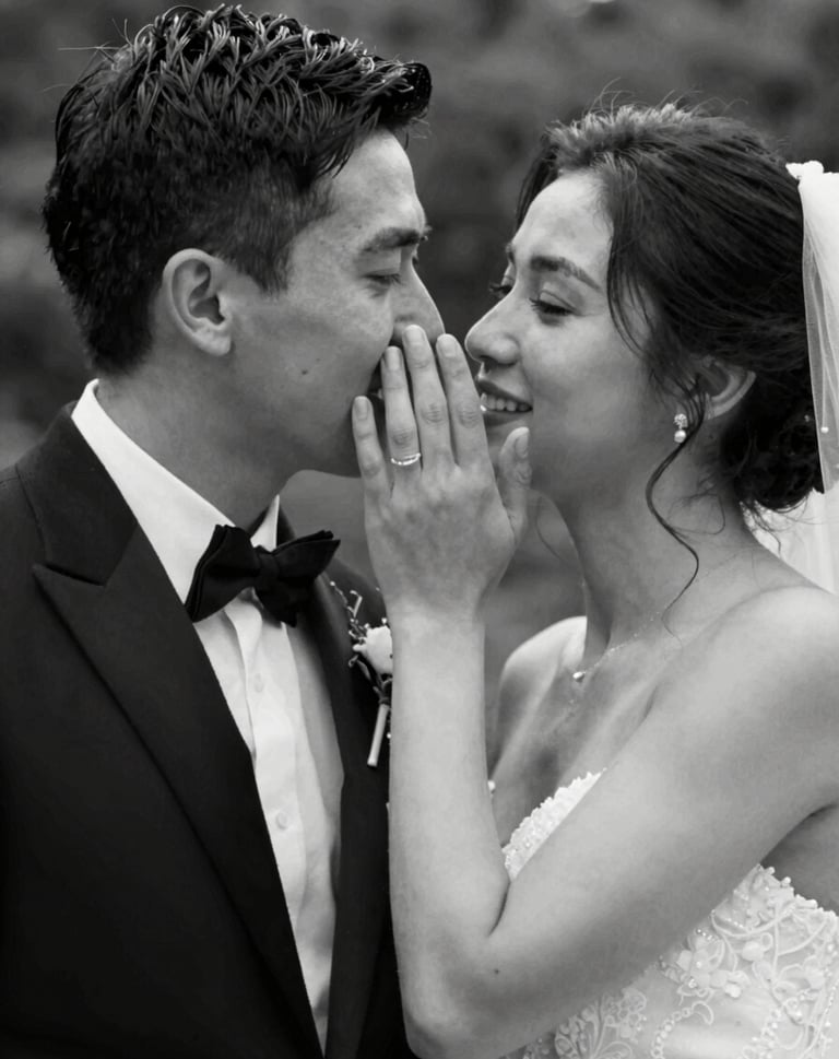 A black and white cinematic still (#20232B and #F7F5F0) showing a groom whispering to his bride. The composition is intimate and storytelling-focused, with elegant light grain texture.