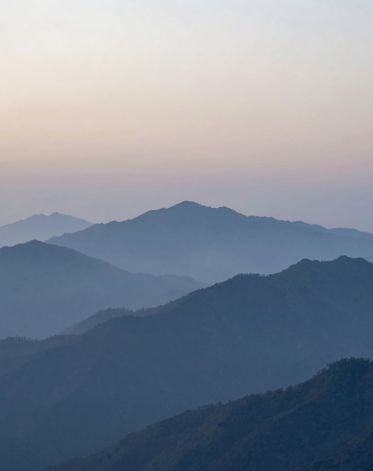 A serene and clean landscape photograph of a misty mountain range at dawn. The colors transition from pale fog at the peaks to steel blue in the valleys. Minimalist composition focusing on natural scale and silence. International / Western landscape.