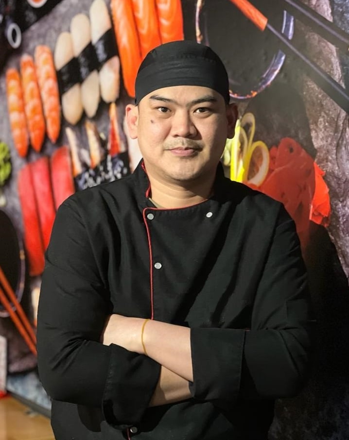 a chef in a black uniform and a black hat