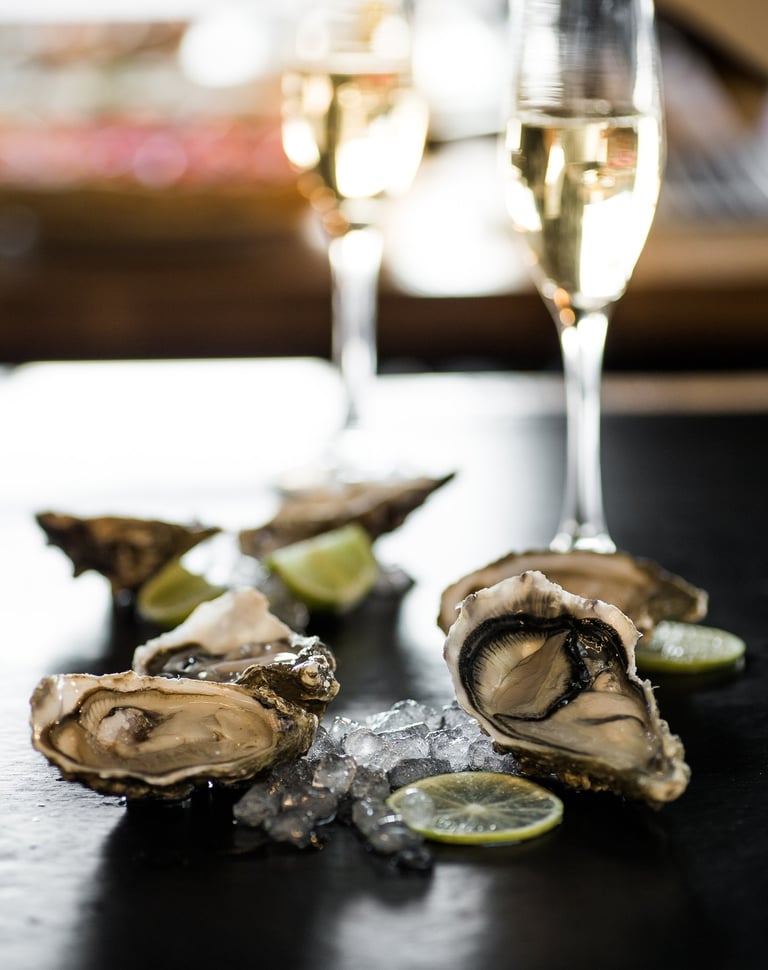 Huîtres ouvertes posées à côté de deux flûtes de Champagne