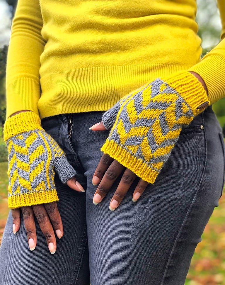 a woman in a yellow sweater wearing a pair of yellow and grey fingerless knitted mittens