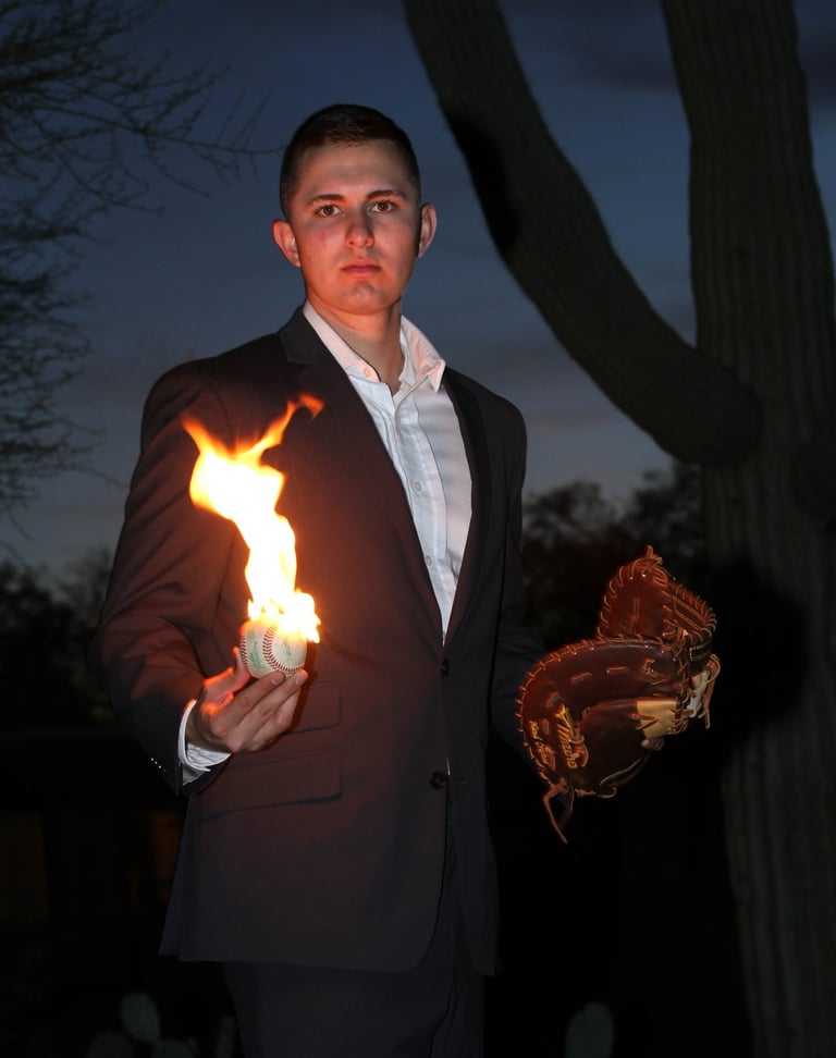 Young man holding a baseball mitt and baseball. The baseball is on fire! Cactus in the background.