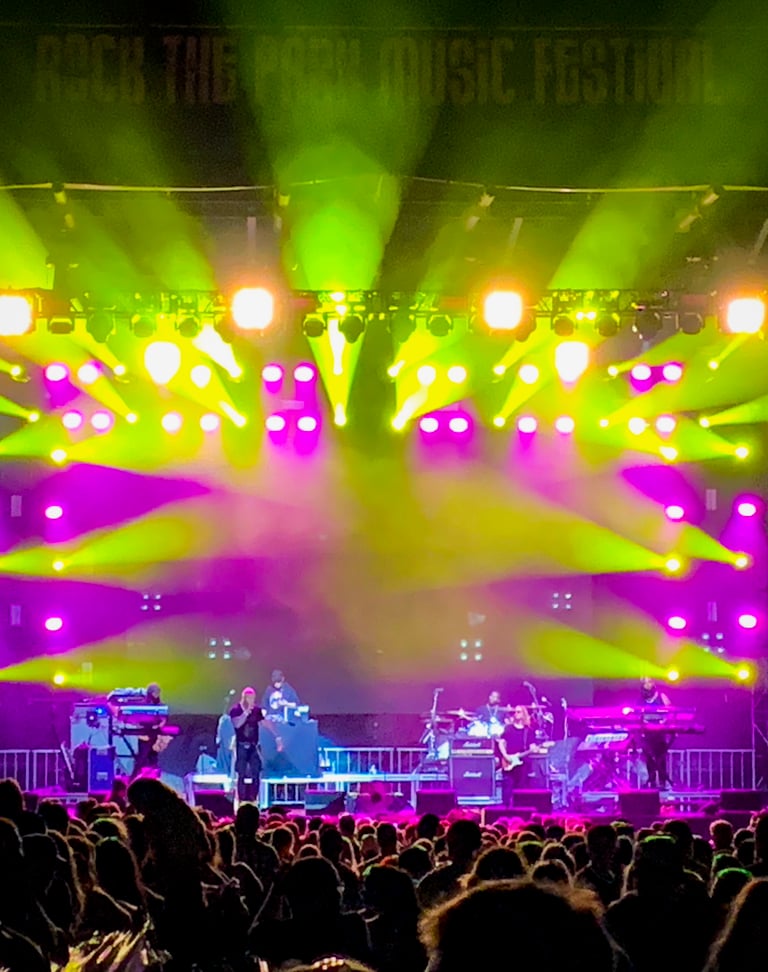 Lots of LED moving head fixtures on an outdoor stage at a music festival.