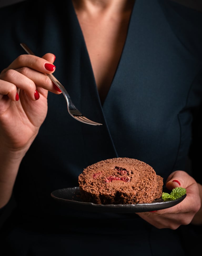 a woman in a black dress holding a fork and a desert