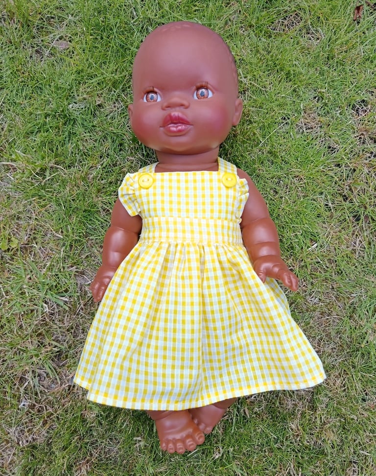 Minikane doll Nia dressed in a yellow gingham dress