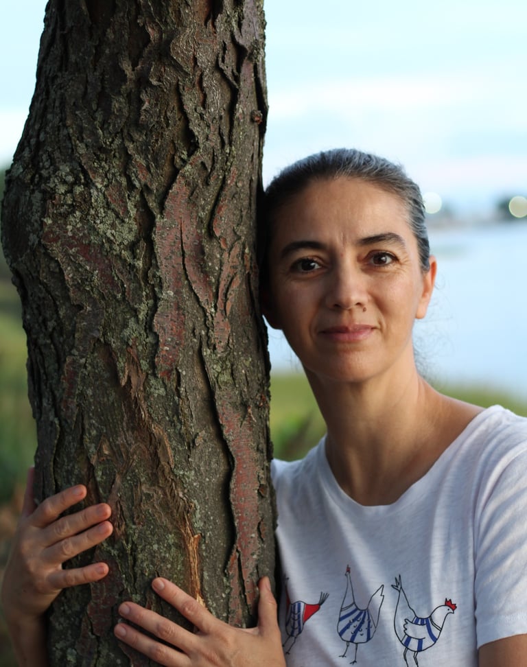 a woman standing next to a tree trunk