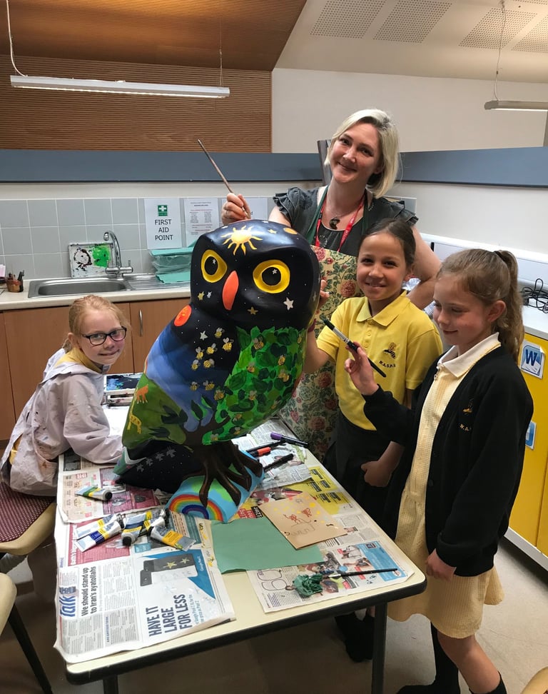 Laura Fearn painting an owl sculpture with pupils from a local school