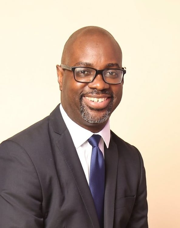 a man in a suit and tie sitting on a stool