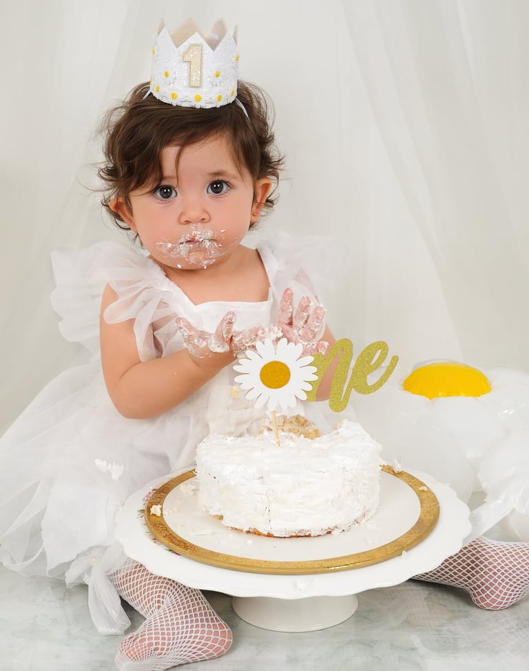 Joyful toddler celebrating a first birthday with a fun and messy cake smash at Pixel Craft Studio.