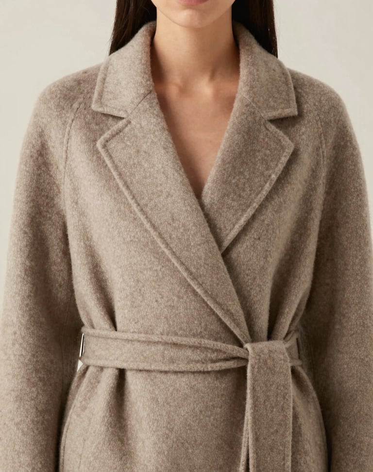 Editorial portrait of elegant women's wool wrap coat in warm taupe, soft studio drape