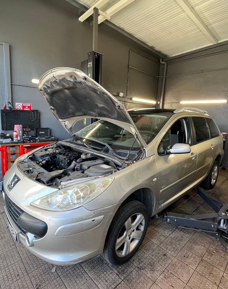 a car with a in a garage with mechanics working on it