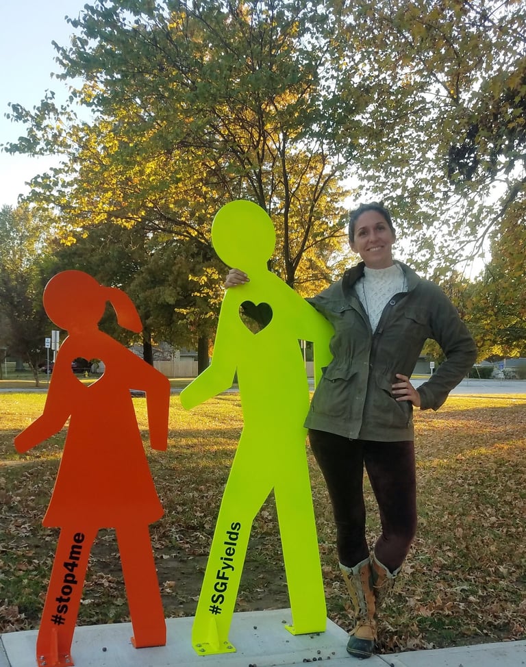 Mandy posing with a sculpture of two walkers