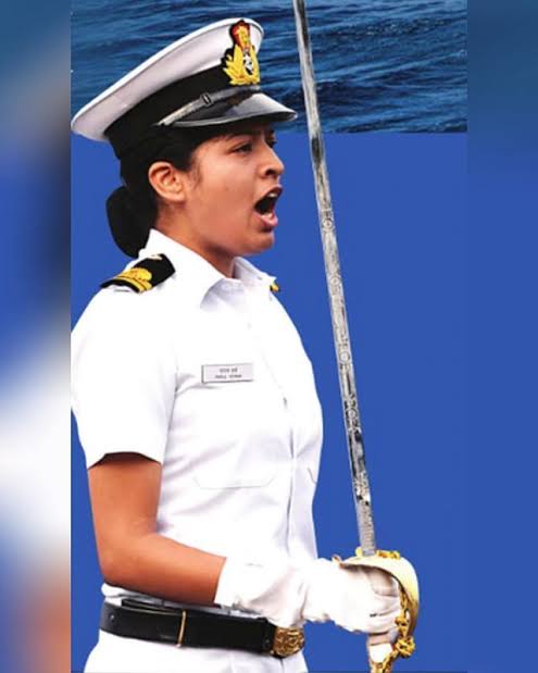 A woman Navy Officer in uniform confidently holds a sword, exuding strength and determination.