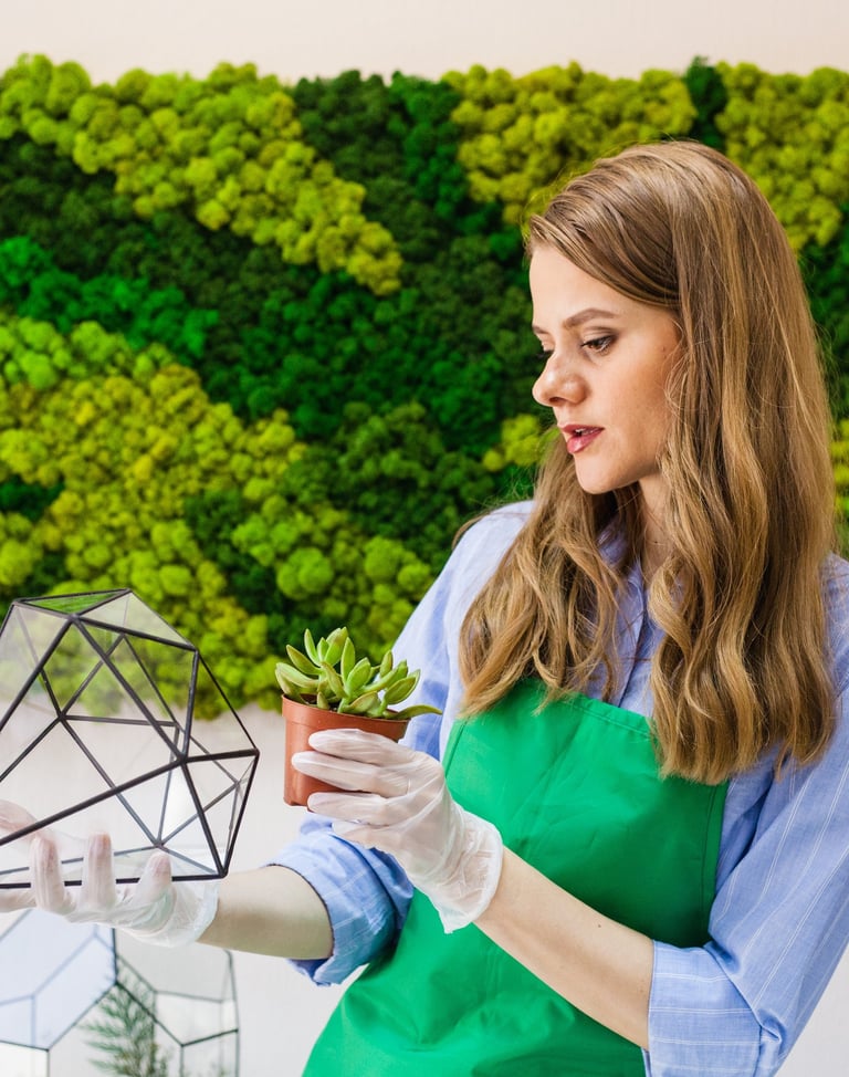 Bir bitki tutan yeşil önlüklü bir kadın. Manisa'da yosun duvar uygulaması ve tasarımı