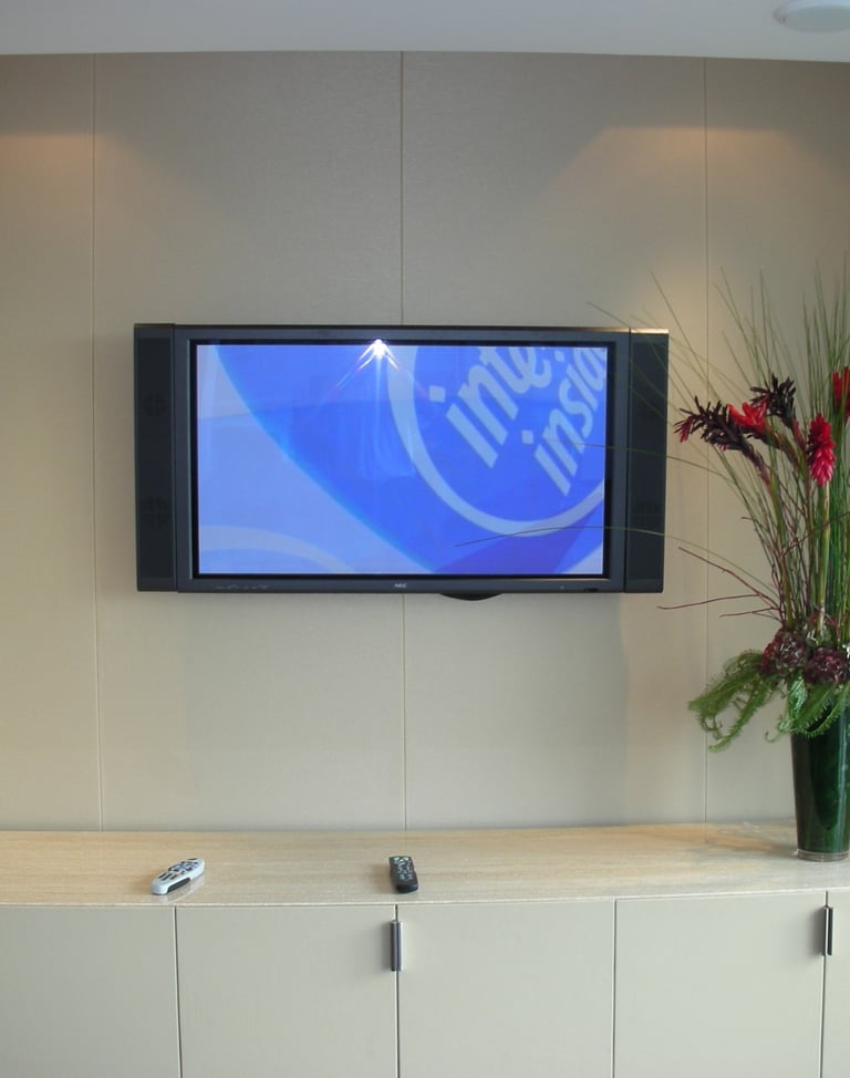 Neutral fabric wall finish around a TV wall with fitted storage unit