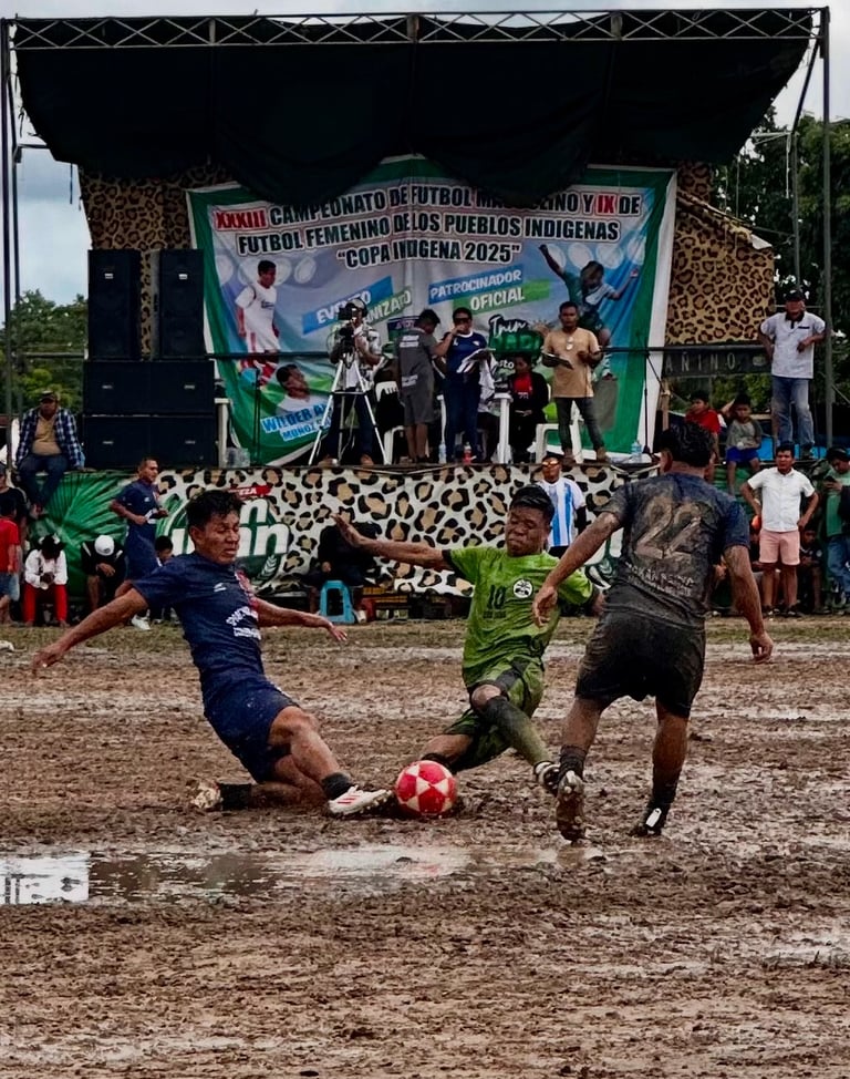 Athletes competing in a muddy indigenous community soccer match at the Copa Indigena tournament.