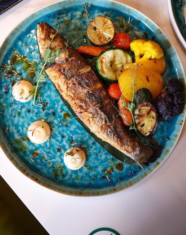 a herring fish on a plate with vegetables