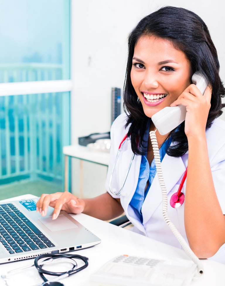 Office staff member talking on the phone to schedule a patient consultation