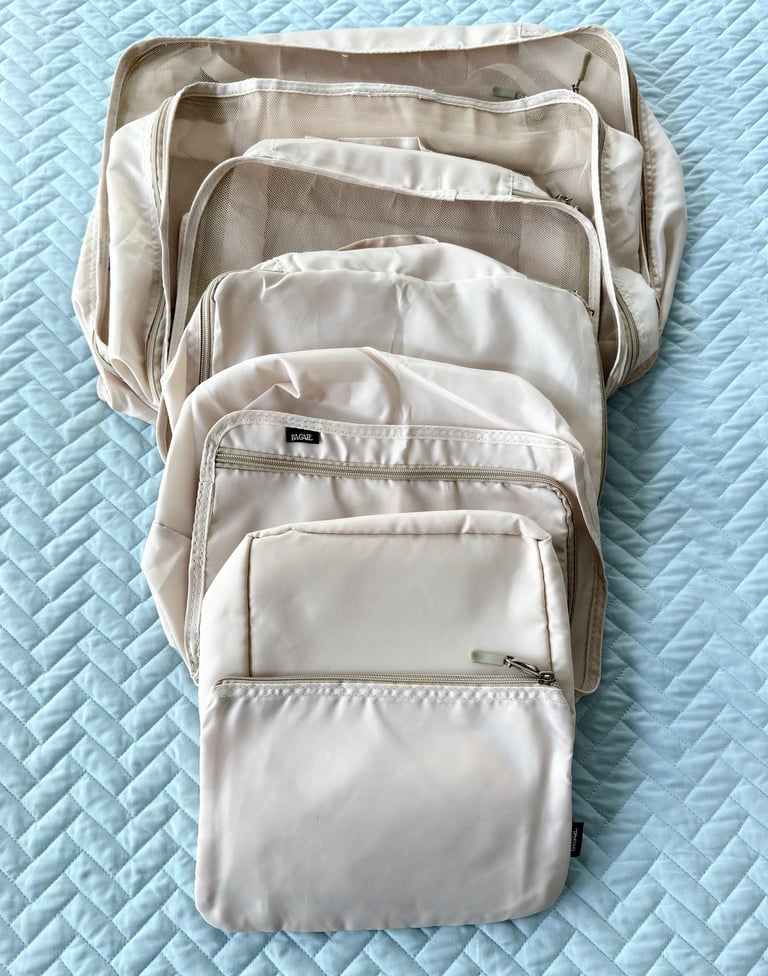 Cream colored packing cubes laid out for organizing clothing during travel