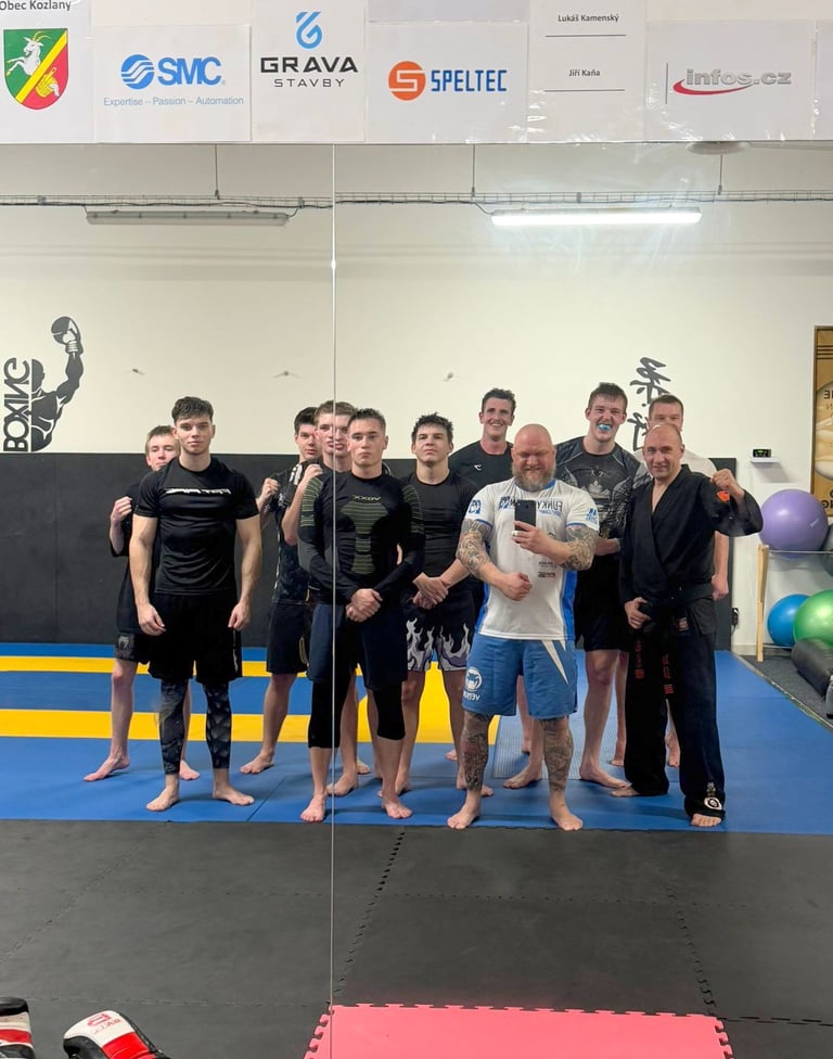 A group of MMA and martial arts athletes posing for a mirror selfie during training in a combat sports gym.