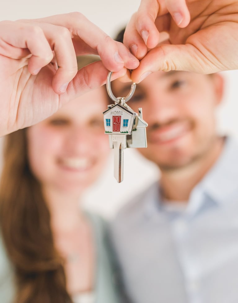 happy couple holding keys to a house after reading the guidebook created your neighbourhood surveyor