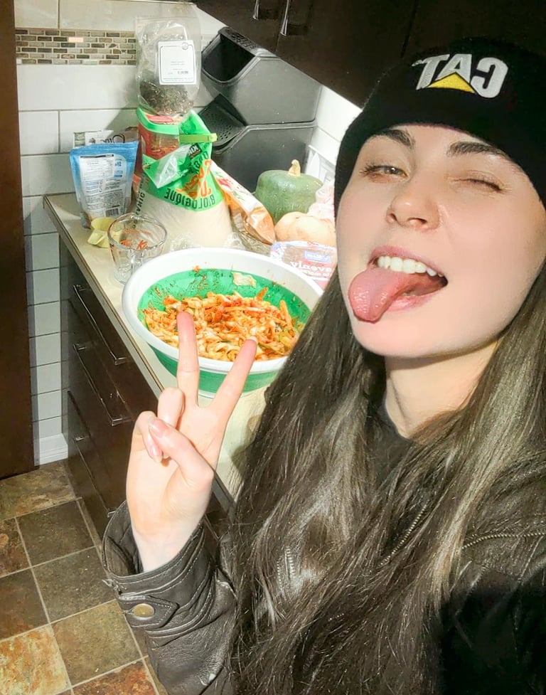 a woman with long hair and a hat on with her tongue stuck out in front of kimchi