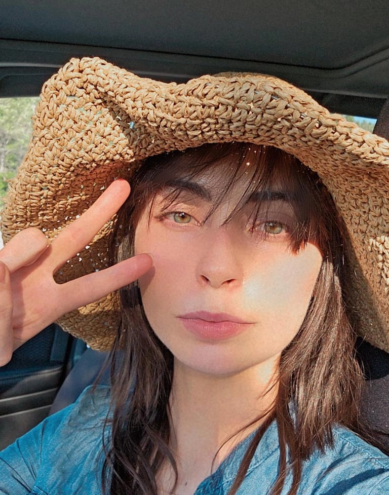 a woman in a straw hat with a straw hat on doing peace sign