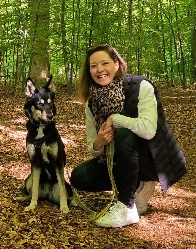 Hundetrainerin mit Hund bei Spaziergang im Grünen