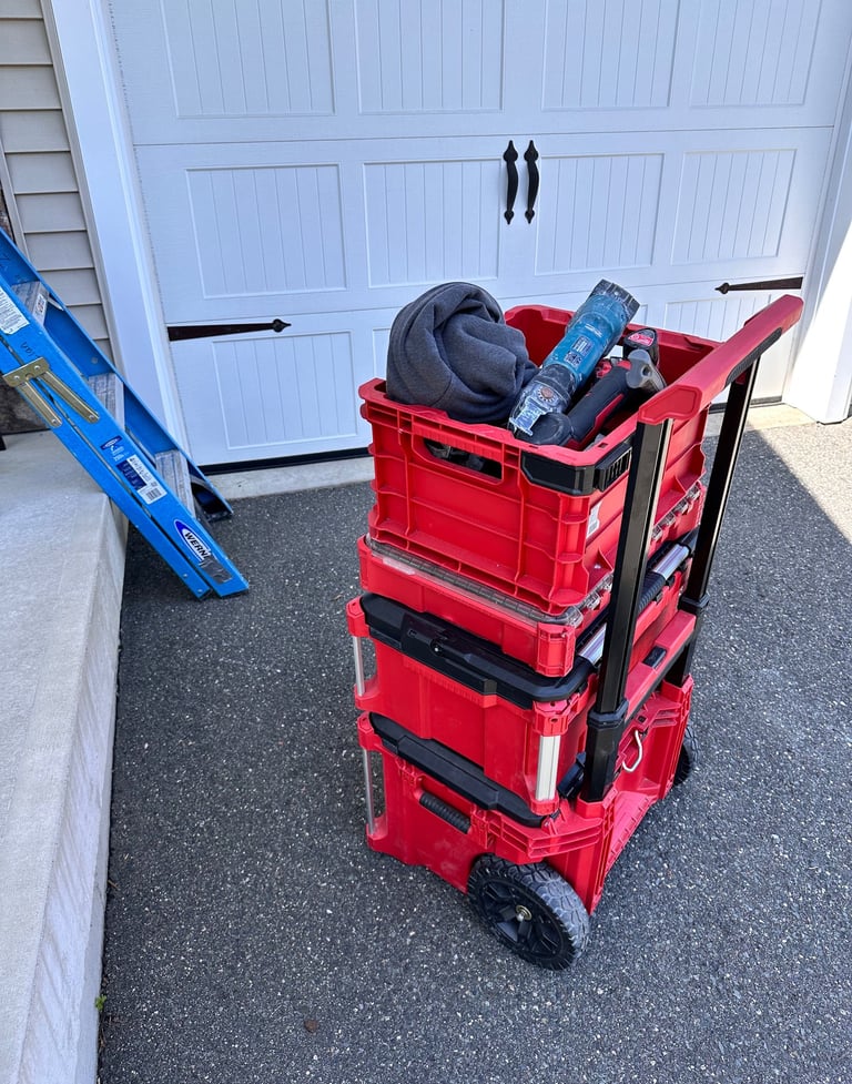 Red rolling modular tool box system stacked on a driveway next to a blue ladder.