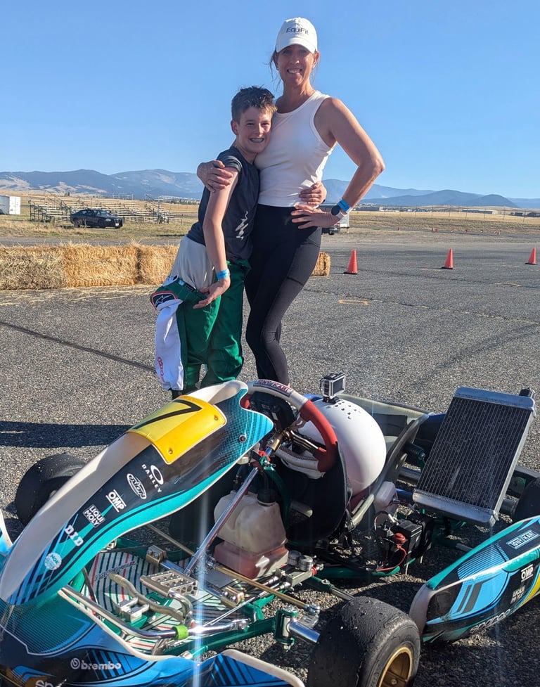 a woman and a boy are standing next to a race car
