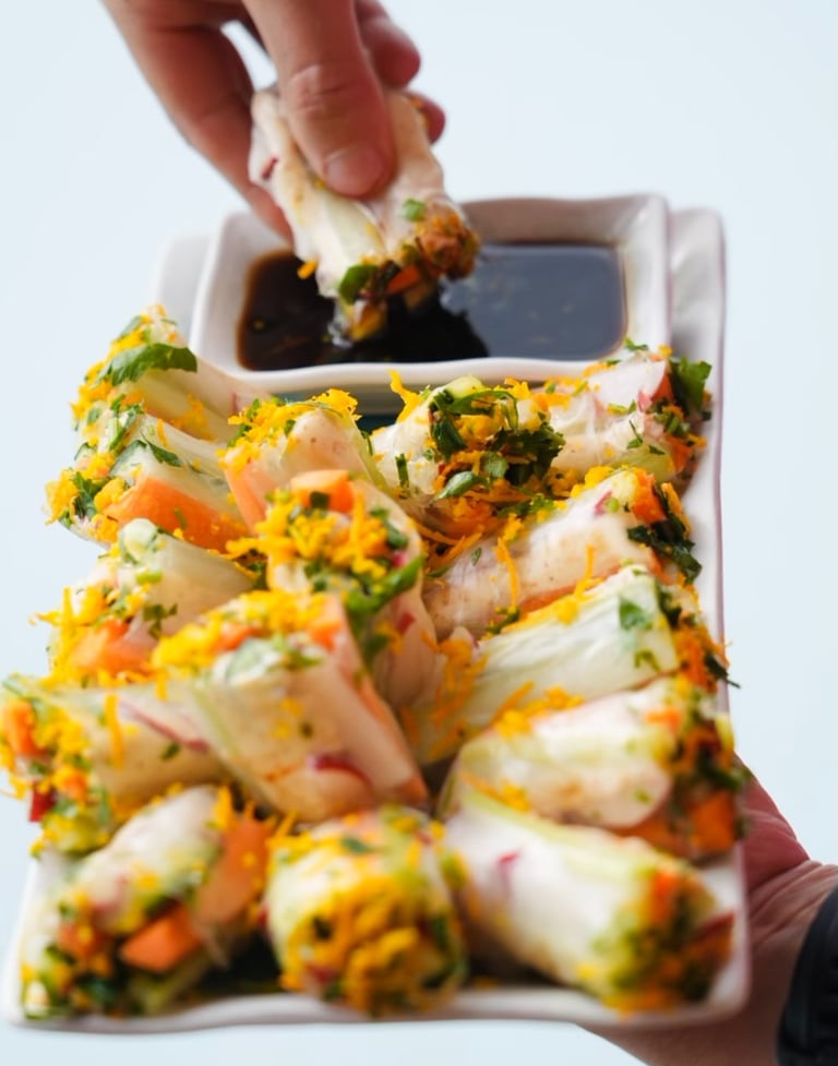a person holding a plate with food and dipping sauce