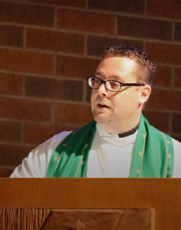a pastor standing at a podium with a priest