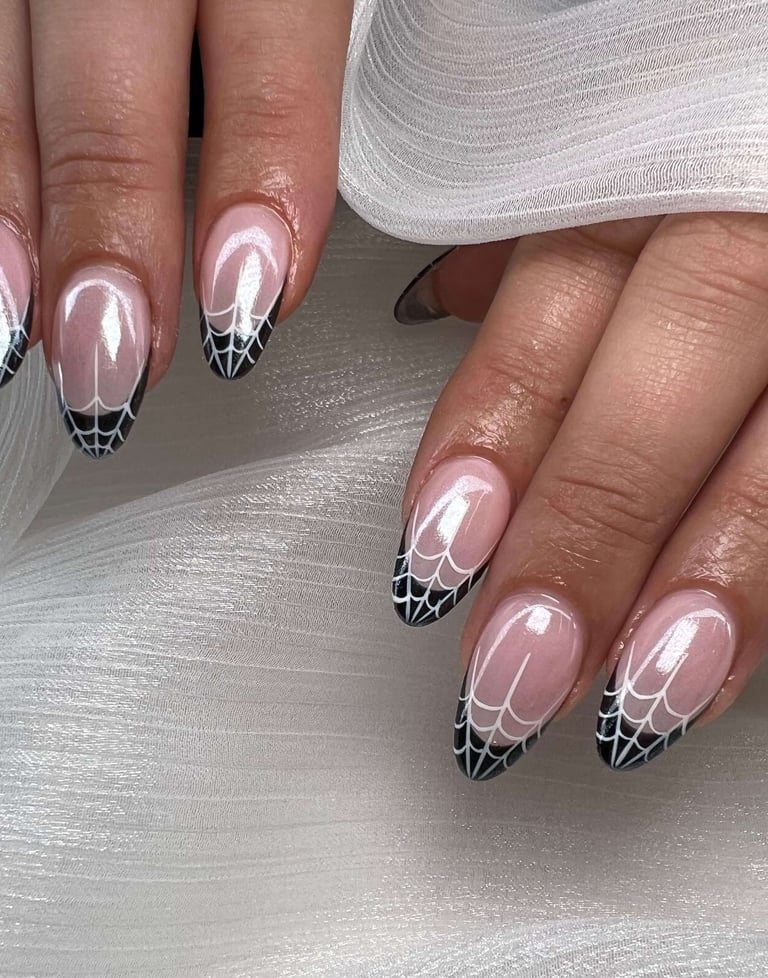 Almond-shaped fall nails with black and white spiderweb tip design.