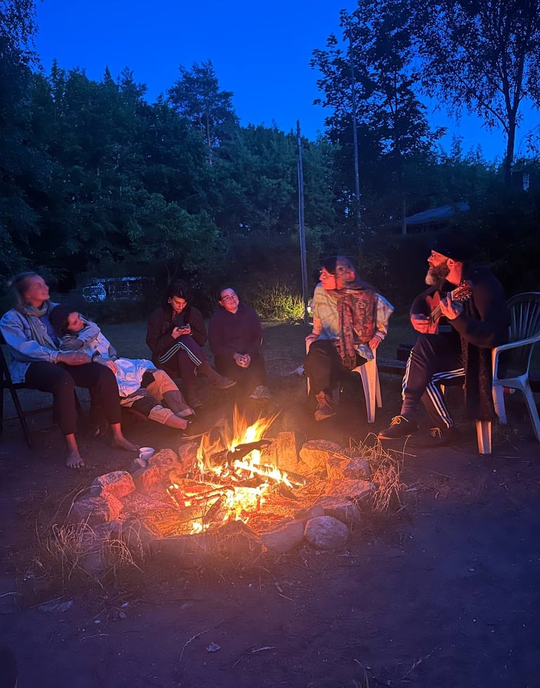 People sitting around the fire making music - photo by Birdy
