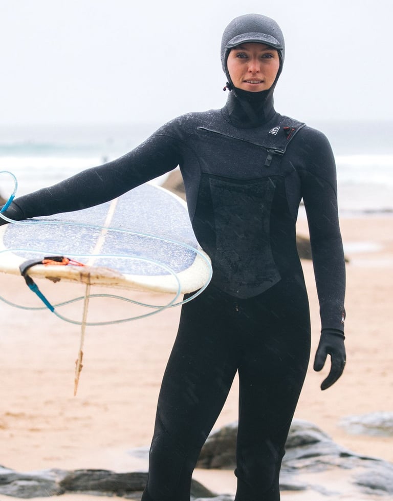 A female surfer in full winter wetsuit equipment