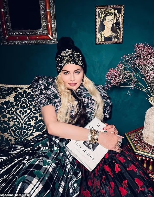 Madonna reading book in vintage-inspired room with a Frida Khalo painting.