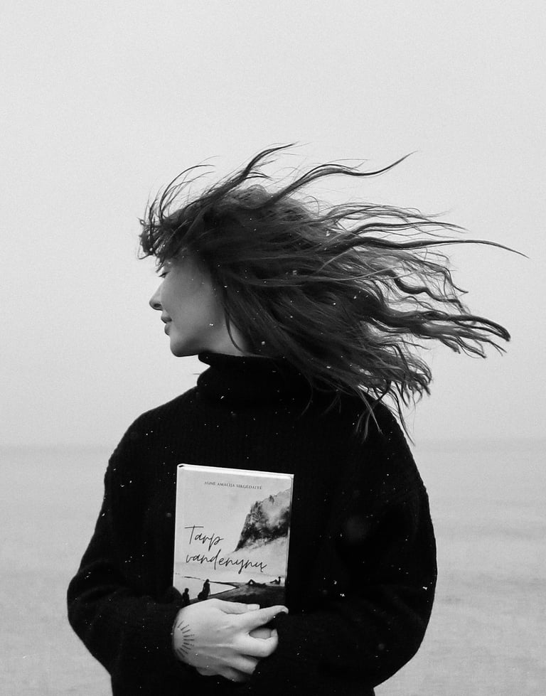 a woman standing on a beach holding a book