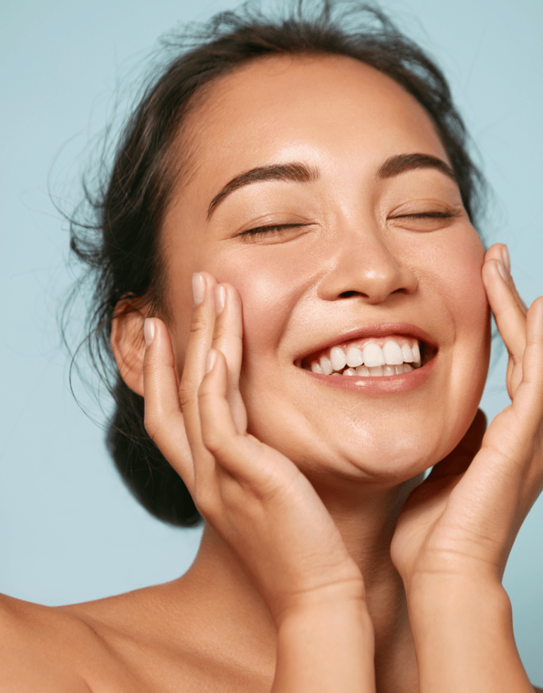 Smiling woman with clear, healthy skin touching her face, representing smooth skin