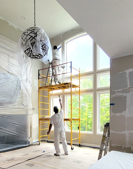 two painters in painter whites painting large living room