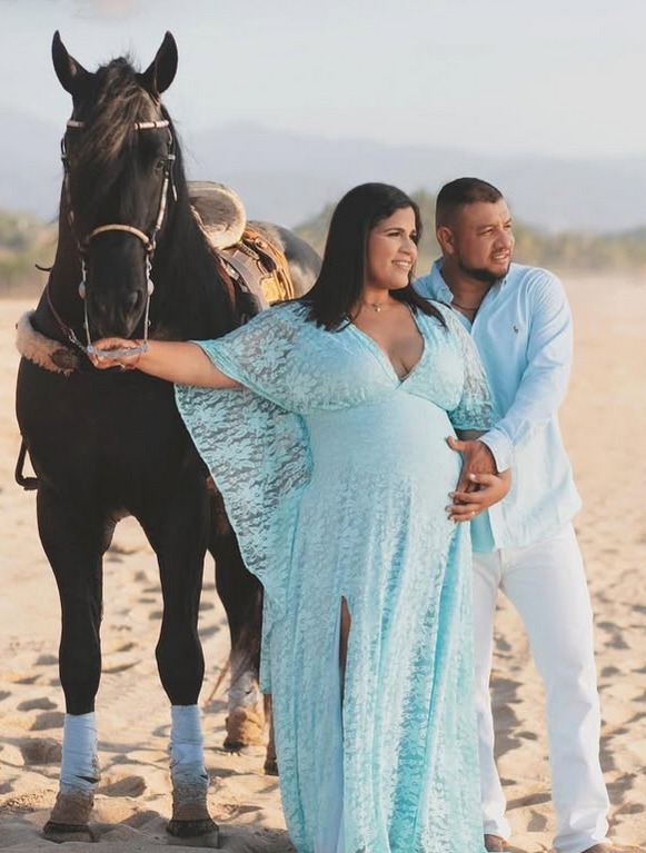 una mujer embarazada con su esposo y un caballo en la playa