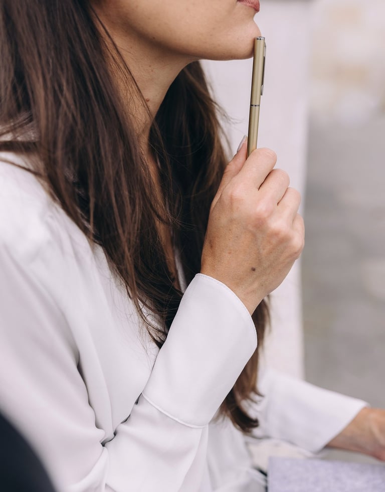 a woman touching her chin with the pen in her hand