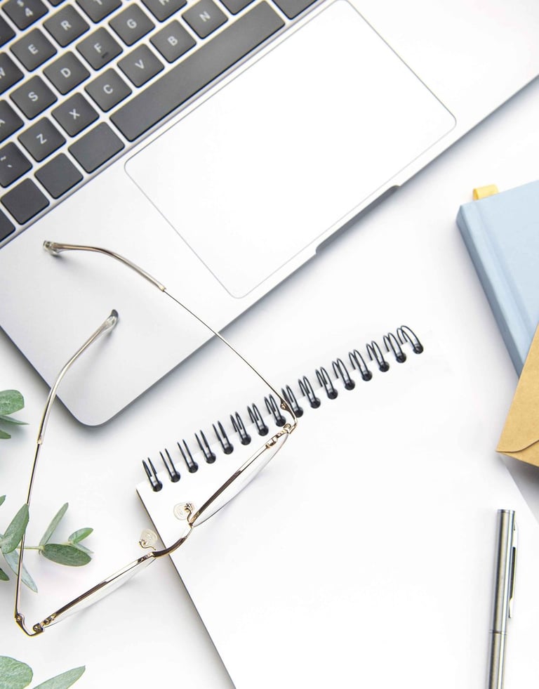 Image of a notebook with a laptop, glasses and eucalyptus leaves