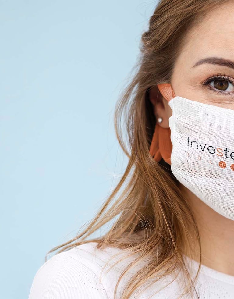 Mujer en primer plano con una mascarilla con el logo de Investén ISCIII