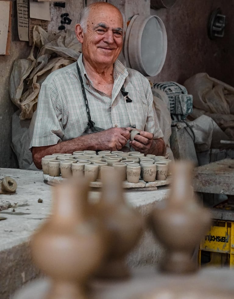Traditional ceramist in Assemini shaping small handcrafted clay pieces inside his workshop, Sardinia
